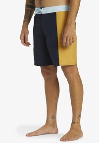 Badeshorts mit einem Farbschnitt-Design in Marineblau, Gelb und Hellblau. Elastischer Bund mit Bindeschnur und seitlichen Taschen.