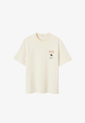 T-shirt en coton crème avec manches courtes, col rond et un motif imprimé d'un hérisson avec le texte "FORÊT !" sur la poitrine.