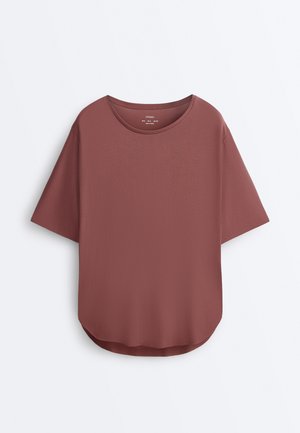 T-majica z ročnimi kratkimi rokavi in okroglim izrezom v barvi vijolično roza s ukrivljenim spodnjim robom, predstavljena na enostavni belem ozadju.