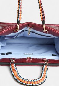 Bordeaux synthetische handtas met een blauwe binnenkant, gevlochten meerkleurige handvatten, gouden accenten en een binnenzak met rits.