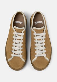 Sneaker in suede marrone con lacci bianchi e logo. Forma arrotondata, superficie testurizzata e suola in gomma a contrasto. Design casual per un uso quotidiano.