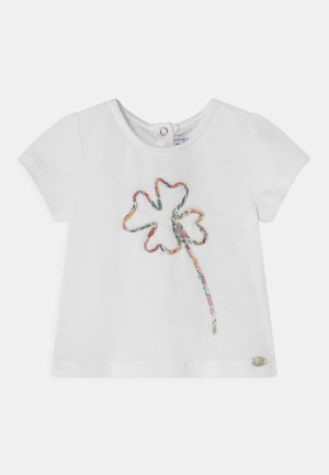 T-shirt bébé blanc à manches courtes avec un contour de trèfle à motif floral coloré sur le devant et une petite fermeture à boutons dans le dos.