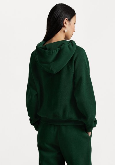 Groene hoodie met een grote, verstelbare capuchon, elastische boorden en een losse pasvorm. Gemaakt van zacht materiaal met een gladde textuur.