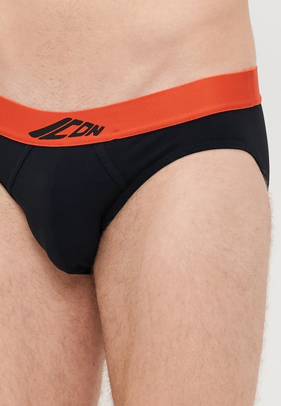 Μαύρα σλιπάκια με φαρδύ πορτοκαλί λάστιχο που διαθέτει το λογότυπο "LDN". Απαλή ύφανση με λεία υφή και στυλ που αγκαλιάζει το σώμα.