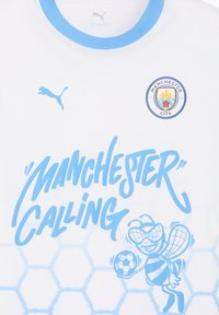 Cămașă albă cu mâneci scurte, cu accente albastre deschise, textul "MANCHESTER CALLING" și un desen cu un bondar ținând o minge de fotbal. Fundal cu un model hexagonal.