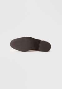 Καφέ δερμάτινη σόλα παπουτσιού με λείο φινίρισμα, διαθέτει υφή με σχέδιο πρόσφυσης και μια ελαφριά καμάρα. Περιλαμβάνει μια ορθογώνια εκτύπωση λογότυπου.