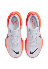 Nike ZoomX futócipők, könnyű és légáteresztő fehér felsőrésszel, narancssárga kiemelésekkel, fekete Swoosh logóval és fűzős kialakítással.