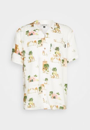 Chemise à manches courtes en tissu blanc avec un imprimé de chameau et de palmier. Boutonnage à l'avant, poche poitrine et coupe décontractée.
