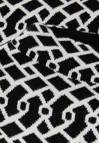 Schwarz-weißes Strickgewebe mit einem geometrischen Muster aus miteinander verbundenen Formen und Rauten sowie einer weichen Textur.