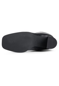 Semelle de chaussure en cuir noir à design plat, avec une surface texturée et des rainures subtiles pour la traction. Bords nets et construction simple.