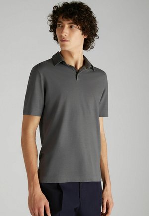 Polo a maniche corte di colore grigio scuro, realizzato in tessuto morbido. Presenta un colletto con due bottoni e una vestibilità rilassata.