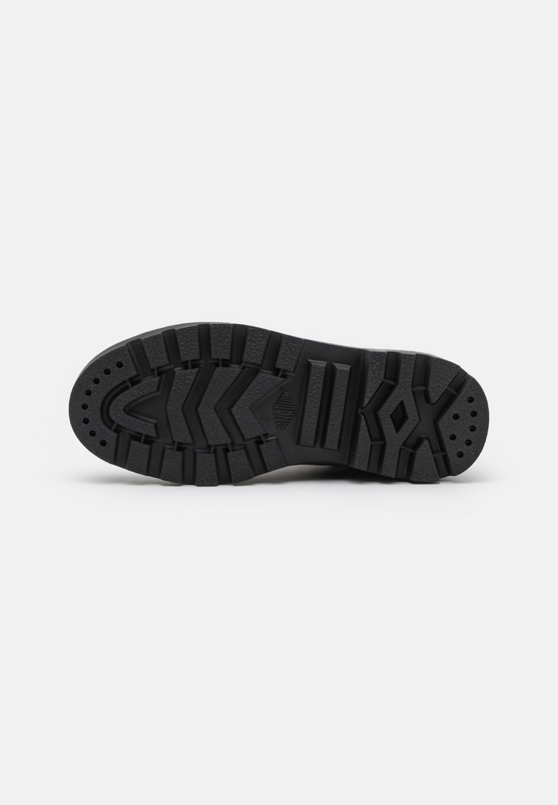 Semelle de chaussure en caoutchouc noire avec des rainures profondes, présentant un motif en zigzag, des bords renforcés et de petits trous de drainage pour l'adhérence et la durabilité.