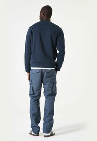 Marineblauwe sweatshirt met textuurpatroon, ronde hals en geribde cuffs, gecombineerd met blauwe cargobroek met zakken en een taps toelopende pasvorm.