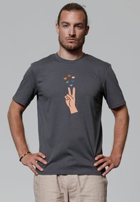 Grijze katoenen t-shirt met een geprinte handgebaar en kleurrijke harten erboven, ronde halslijn en korte mouwen.
