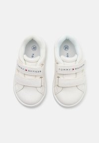 Sneakers bianchi per bambini con pelle testurizzata, due cinturini in Velcro e un interno azzurro chiaro. Presentano il marchio "Tommy Hilfiger" sui cinturini. Taglia 20.
