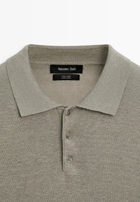 Polo en tricot gris clair avec col et trois boutons, étiquette indiquant 100 % lin par Massimo Dutti, fabriqué en Chine.