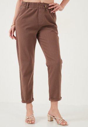 Brune, lette bukser med elastisk talje, frontknap, sidelommer, tætsiddende pasform og opslået kant. Glat stofoverflade.