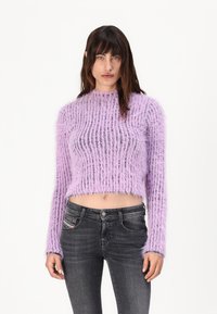 Fialový, huňatý svetr s žebrovaným vzorem, dlouhými rukávy a krátkým střihem, kombinovaný s tmavými skinny džíny. Texturovaná příze a volný úplet.