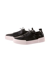 Para czarnych skórzanych sneakersów wsuwanych z białymi grubymi gumowymi podeszwami i elastycznymi kołnierzami na kostkach, przedstawiona na białym tle.
