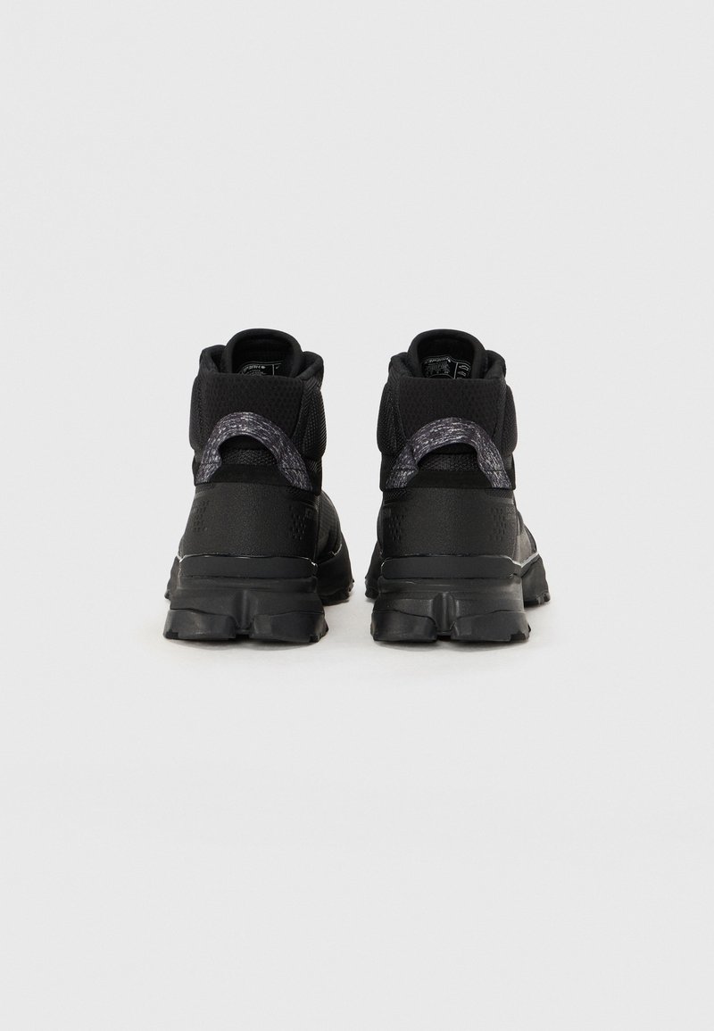Czarne wysokie buty sportowe z textured mesh wierzchem, wyściełanym kołnierzem i wzorzystymi akcentami. Gruba gumowa podeszwa z wyraźnym bieżnikiem.