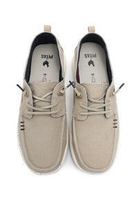 Beige canvas shoes with laces, featuring a textured finish, white speckled sole, and black accent stitching. Interior lining in navy.