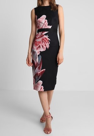 Czarna sukienka midi bez rękawów z dużym różowo-czerwonym kwiatowym wzorem, dopasowana w talii, noszona z różowymi sandałami na wysokim obcasie z paskami.
