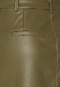 Jupe en cuir vert olive avec une texture lisse, dotée d'une poche arrière et de coutures visibles sur le côté.