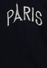 Dunkelblaues T-Shirt mit dem Wort "PARIS" in Weiß, wobei das "A" durch eine stilisierte Skizze des Eiffelturms ersetzt ist.