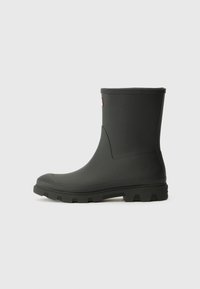 Black rubber ankle boot with a textured, molded sole and smooth upper; features a rounded toe and a subtle logo accent on the side.