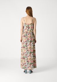 Robe maxi avec un motif floral, fines bretelles, corsage froncé et taille élastique. Le matériau semble léger avec une texture douce.