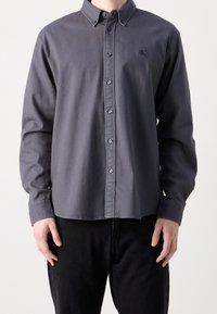 Harmaa pitkähihaisen puuvillapaita, jossa kaulus, etukappaleen napitus ja pieni kirjailtu logo rinnassa.