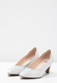 Talons aiguilles argentées en matériau synthétique lisse, avec un petit talon en bois empilé et une semelle intérieure beige douce. Design épuré, sans embellissements.