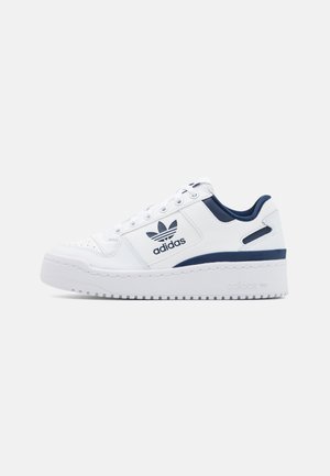 Biały niski sneaker Adidas z granatowymi akcentami, sznurowanym designem, grubą podeszwą i logo Adidas na bocznej części.