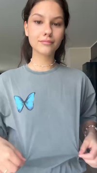 Grå oversized t-shirt med et blåt sommerfugl grafik på venstre side. Blødt stof med en afslappet pasform og korte ærmer.