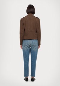 Brown checkered jacket featuring shoulder epaulettes, paired with light blue tapered jeans and black flat shoes. Back view displayed.