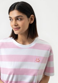 Roze en witte gestreepte T-shirt van katoen, met een ronde halslijn en een kleine oranje glimlachende gezicht logo geborduurd op de borst.