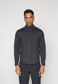 Jacket atlético preto com colar alto, fecho frontal completo e design aerodinâmico. Textura suave e costuras mínimas, adequada para vestuário ativo.