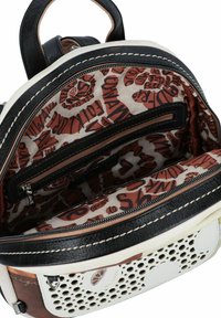 Sac à dos avec un revêtement en cuir perforé blanc et des accents bruns. Intérieur doublé d'un tissu à motif et comprenant une poche zippée.