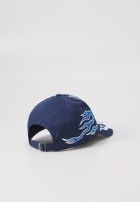 Boné de basebol azul-marinho com bordado de chamas brancas e azuis, faixa ajustável na parte de trás, tecido texturizado e aba curva.