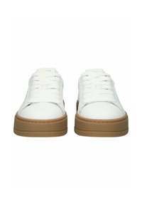 Valkoiset nahkakengät, joissa paksut vaaleanruskeat kumipohjat, valkoiset nauhat ja kielekkeessä kultainen teksti, esitetty edestä päin.