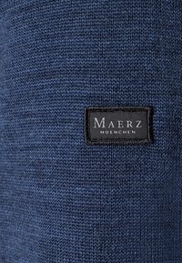 Navy-Strickstoff mit glatter Textur, versehen mit einem schwarzen Etikett mit weißer Schrift "Maerz Muenchen", aufgenäht.