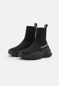 Baskets noires de style chaussette avec une cheville côtelée, une semelle texturée et un détail de logo en blanc. Fabriquées en matériau élastique pour le confort et le soutien.