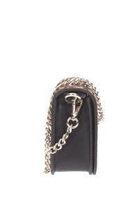 Bolso de mano de cuero negro visto de lado con detalle de cadena dorada y cinta sobre un fondo blanco.