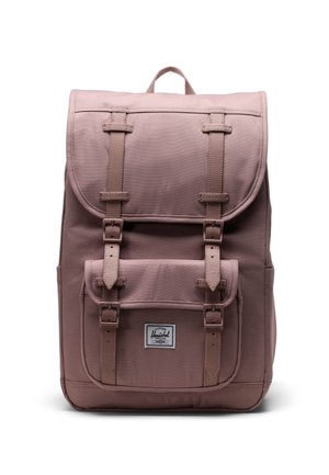 Růžový batoh s plátnovým vnějším obalem, horním klopou, dvěma předními kapsami a nastavitelnými popruhy, s logem na přední straně.