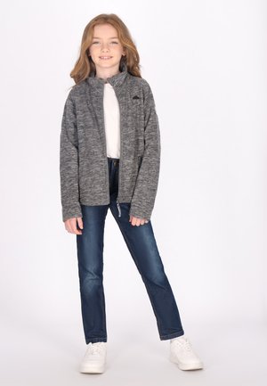 Grå zip-up jakke med høj krave, parret med blå denim jeans og hvide sneakers. Jakken har et subtilt struktureret mønster.