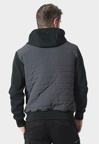 Szara kurtka puchowa z czarną bluzą z kapturem. Posiada pikowaną strukturę z tyłu i ściągacze przy mankietach. Zaprojektowana z myślą o ciepłu i komforcie.