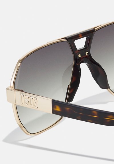Sunglasses with large, tinted lenses and a gold metal frame. The temples are patterned in dark tortoiseshell. Brand inscription "DS02" on the side.
