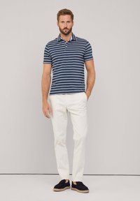 Koszulka polo w niebiesko-białe paski, krótki rękaw, wykonana z mieszanki bawełny. Połączona z białymi spodniami i czarnymi espadrylami. Prosty krój kołnierzyka.