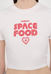White cropped t-shirt featuring red text reading "Fiorucci SPACE FOOD" with a pink heart design below. Soft fabric and classic neckline.