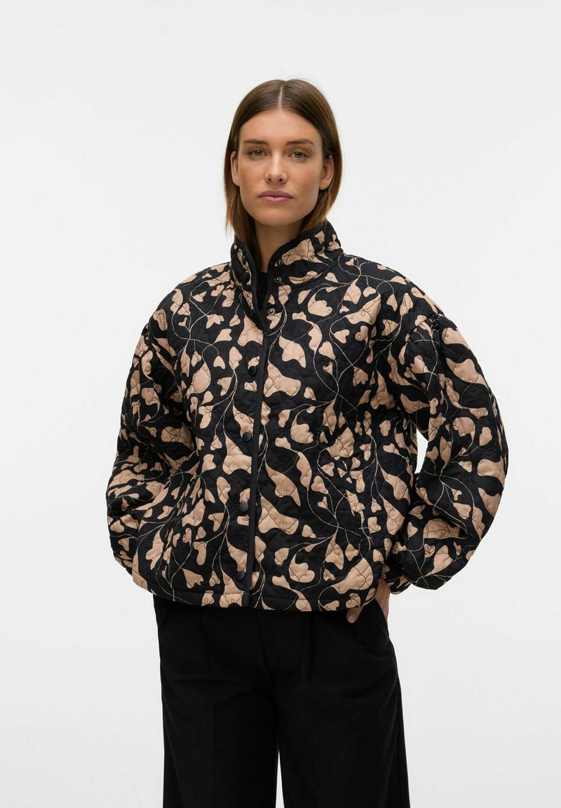 Gequilted jas in zwart en beige met een abstracte bladerenpatroon. Voorzien van een hoge kraag en een ritssluiting aan de voorkant, met oversized mouwen voor extra comfort.